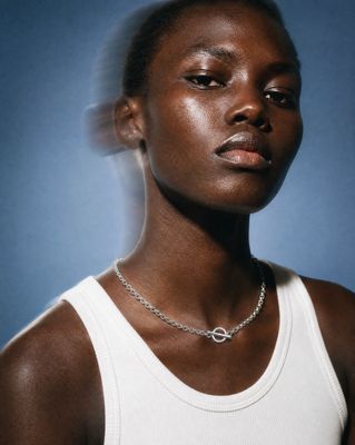 a woman wearing a white tank top and a necklace