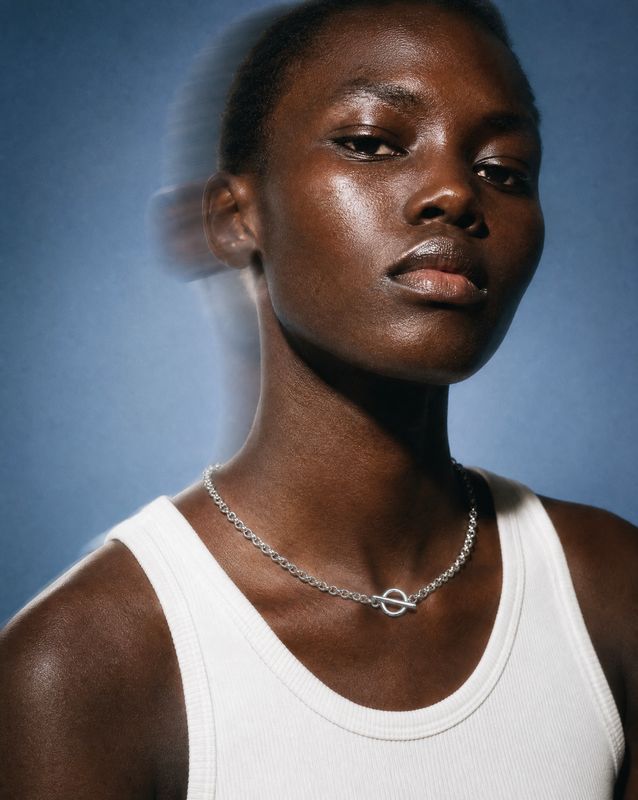 a woman wearing a white tank top and a necklace