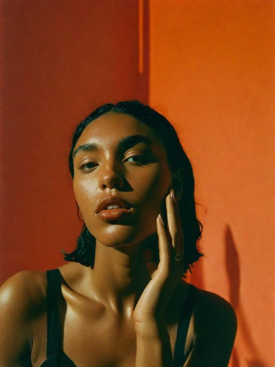 a woman posing for a picture in front of an orange wall