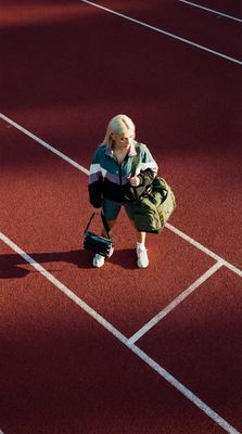 a woman kneeling down on a track with a backpack