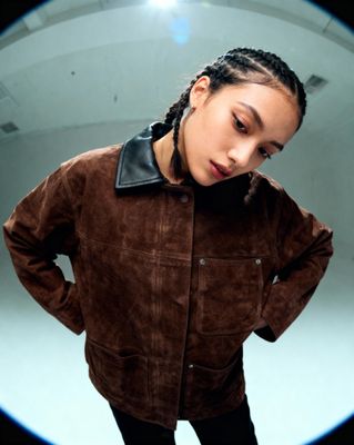 a woman with braids wearing a brown jacket