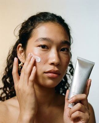 a woman holding a tube of cream in front of her face