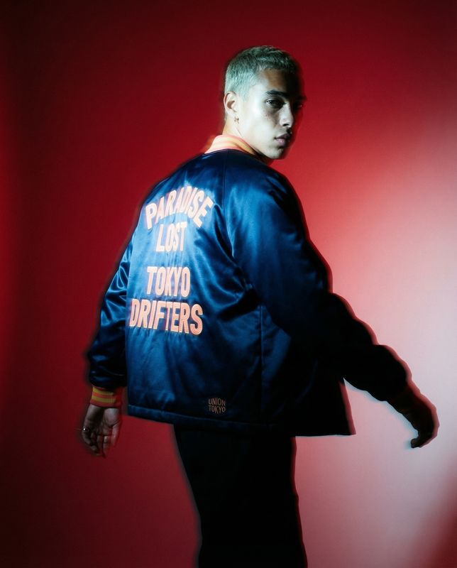 a man in a blue jacket standing against a red background