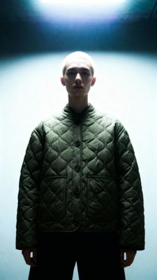 a man with a bald head standing in a dark room