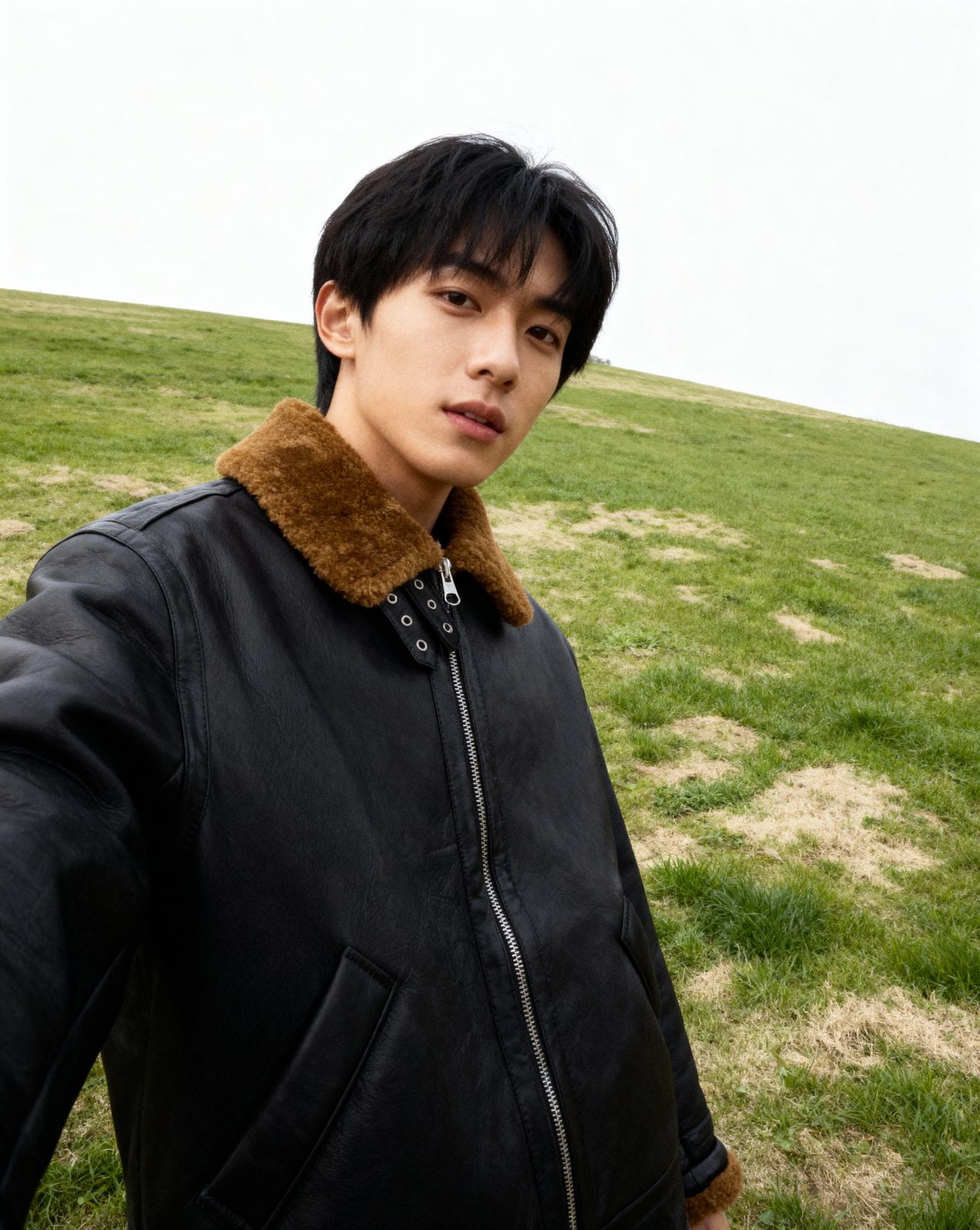 a man in a black jacket standing in a field