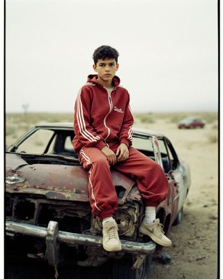 a young man sitting on the hood of an old car