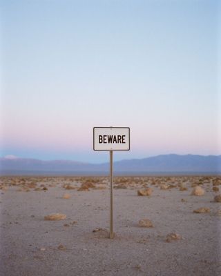 a beware sign in the middle of a desert