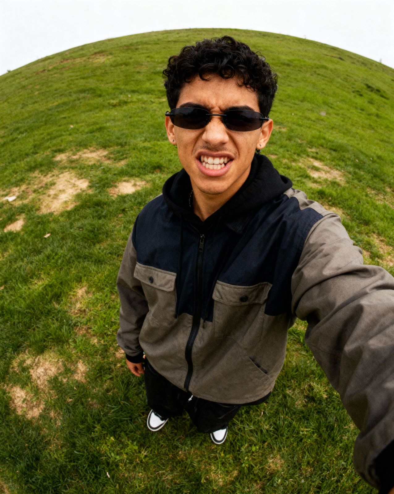 a man taking a selfie in front of a grassy hill