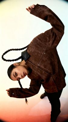 a woman in a brown jacket is doing a hand stand