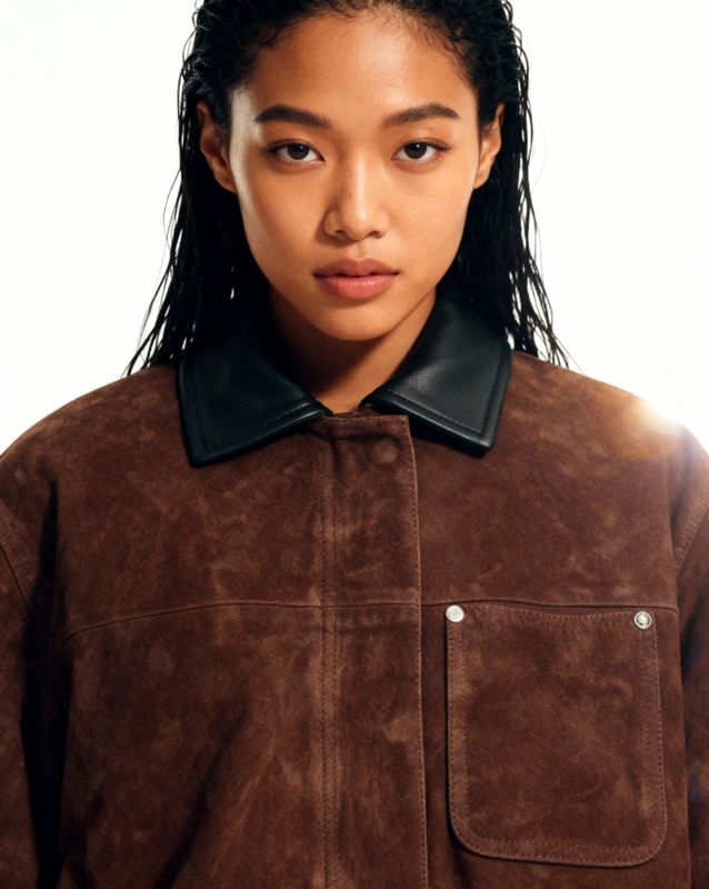 a woman wearing a brown jacket with a black collar