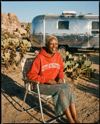 a woman sitting in a chair in front of a camper