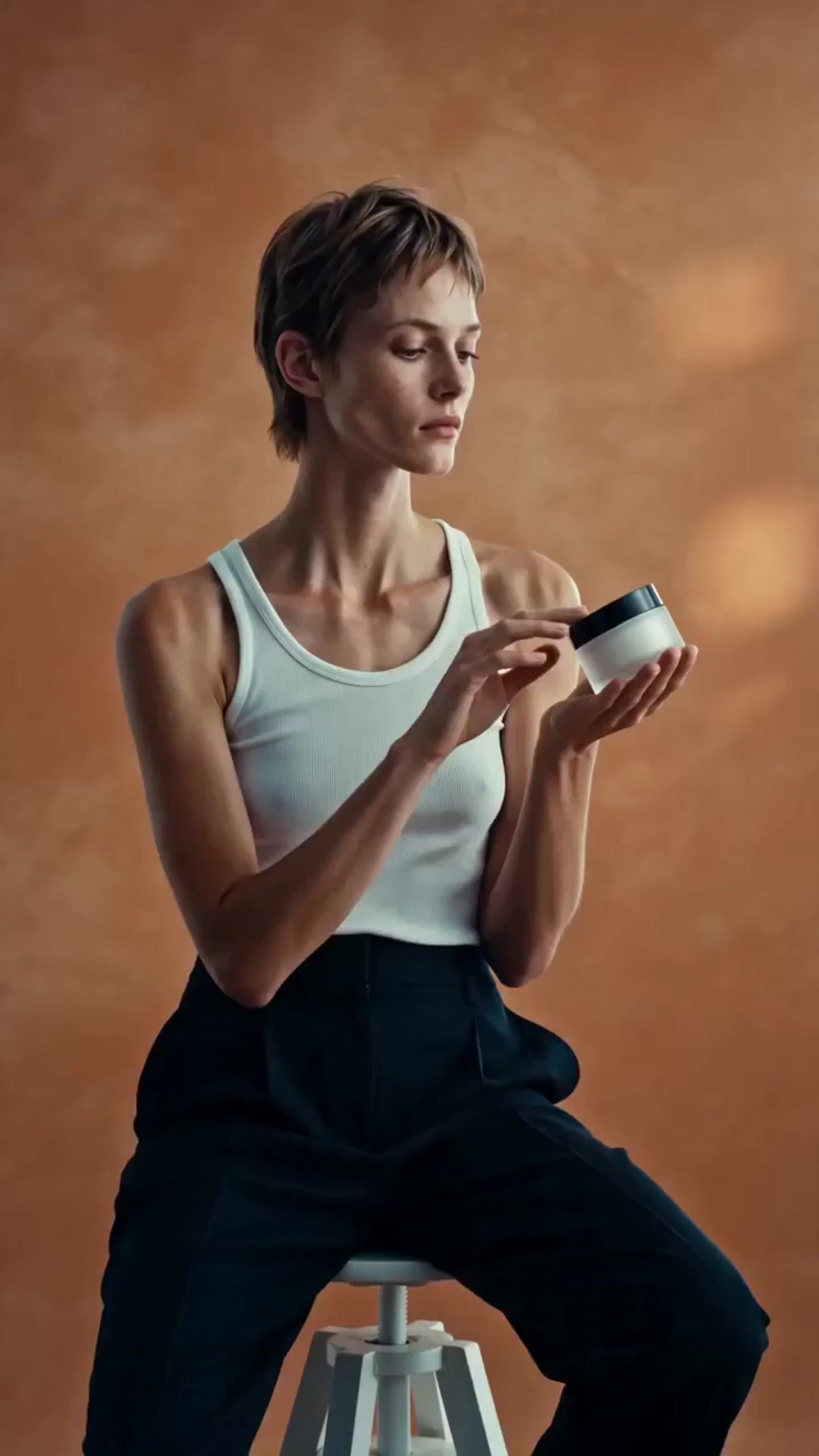 a woman sitting on a stool holding a cup