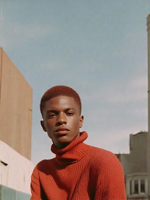 a man in a red sweater standing in front of a building