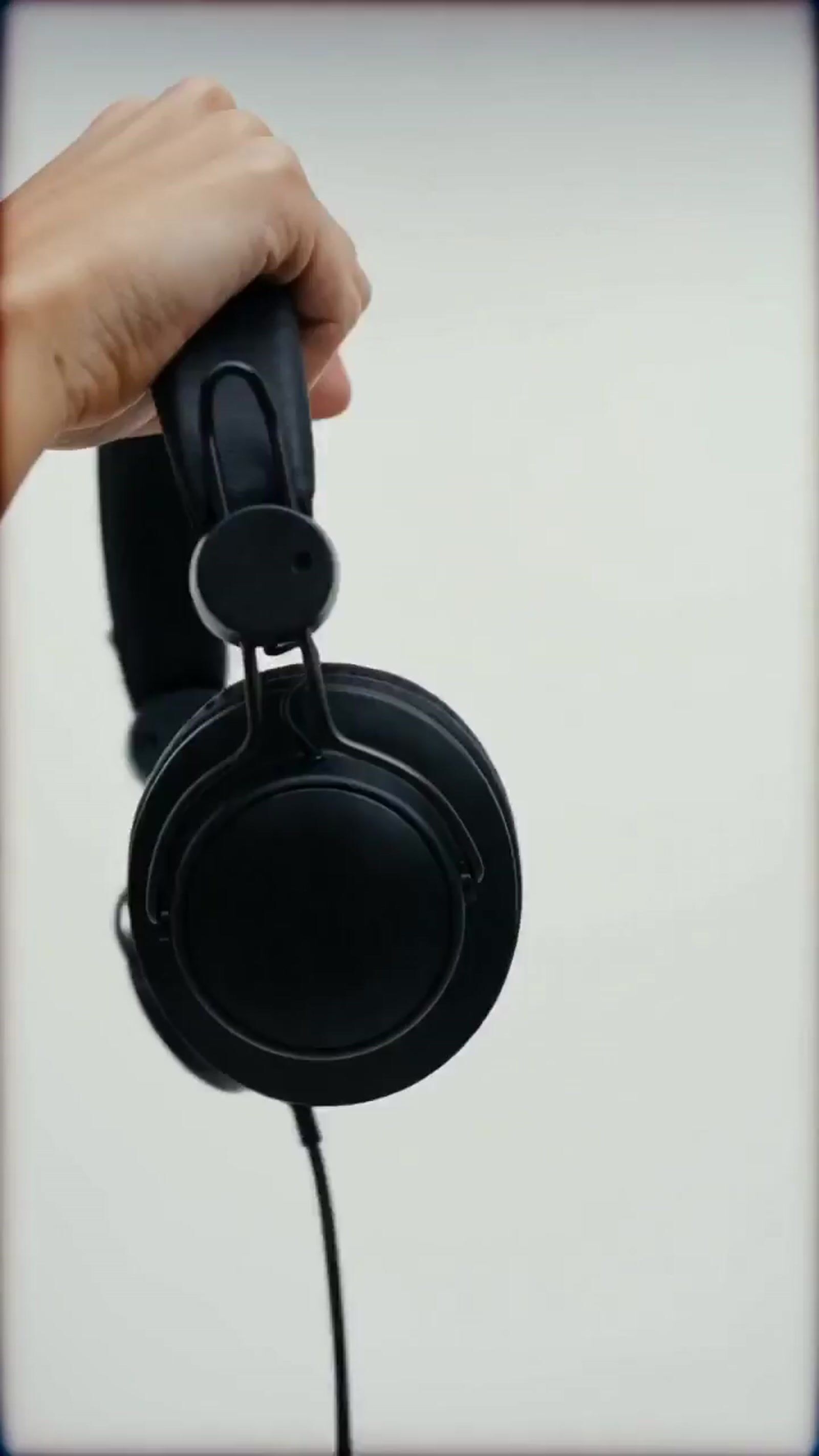 a hand holding a pair of black headphones