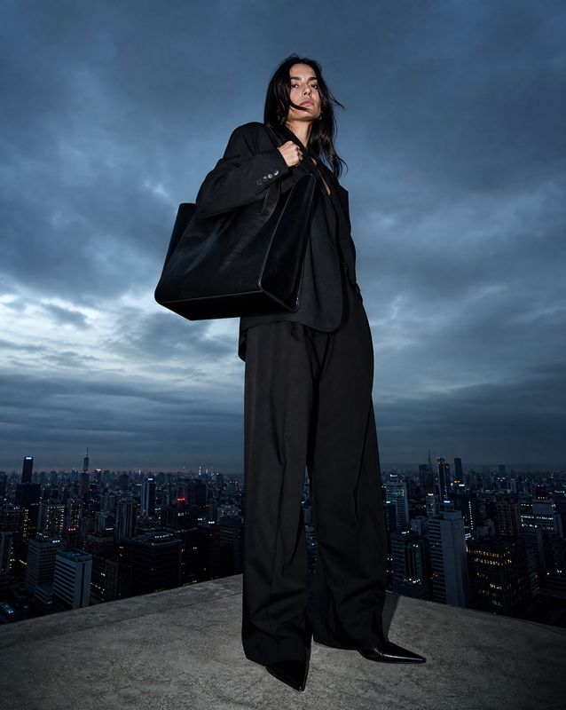 a woman standing on top of a building holding a black bag