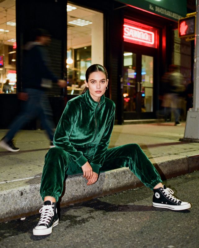 a woman in a green outfit sitting on a curb