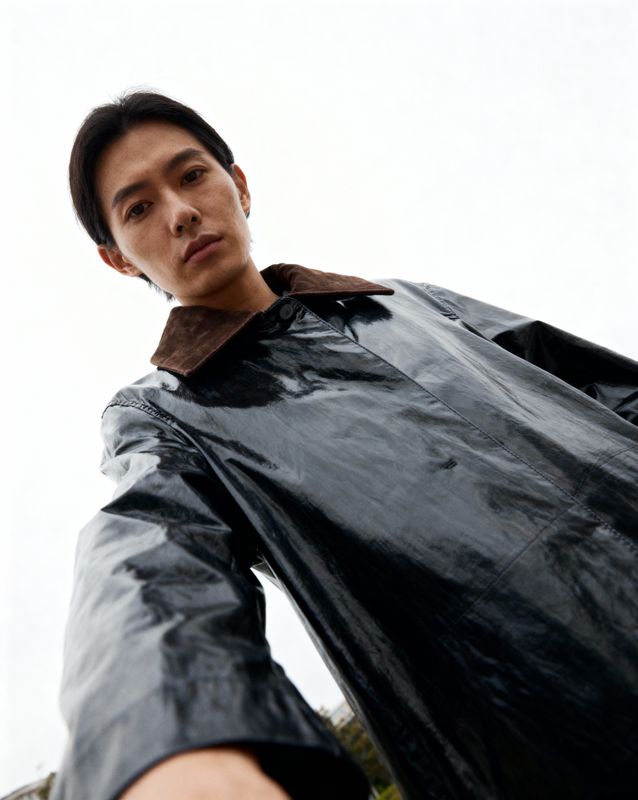 a man in a black raincoat is posing for a picture