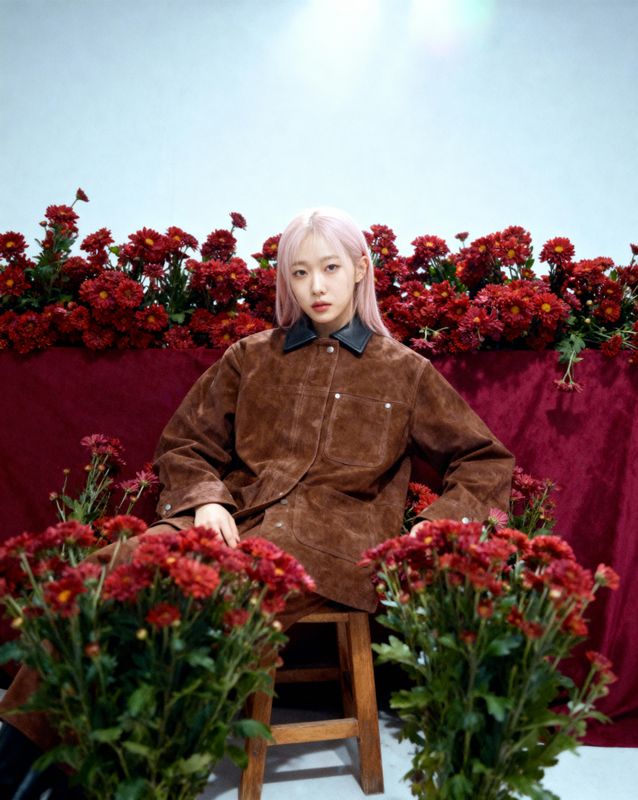 a woman sitting on a chair next to a bunch of flowers