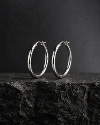 a pair of silver hoop earrings sitting on top of a rock