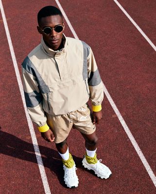 a young man standing on a track wearing sunglasses