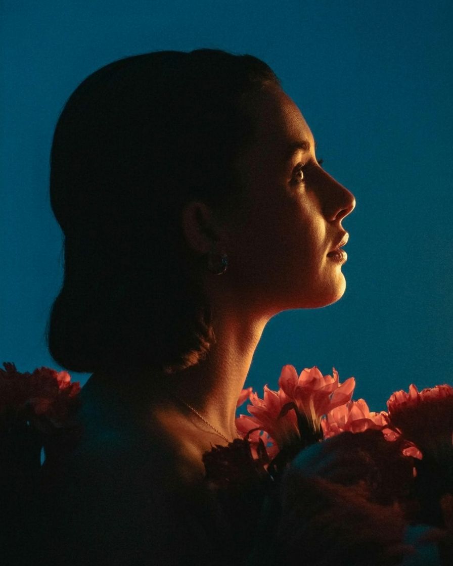 a woman with flowers in her hair looking off into the distance
