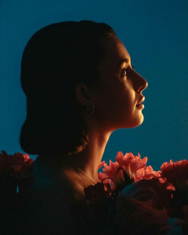 a woman with flowers in her hair looking off into the distance