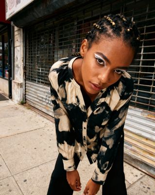 a woman leaning on a skateboard on a sidewalk