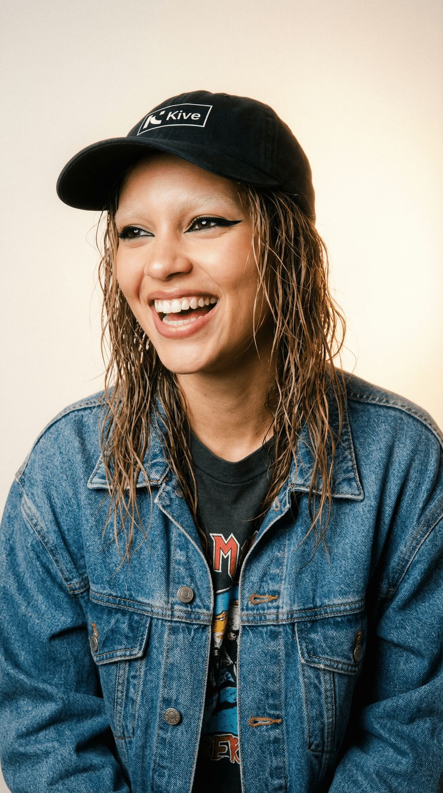a woman with long hair wearing a denim jacket and a hat