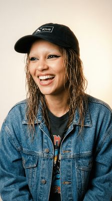 a woman with long hair wearing a denim jacket and a hat