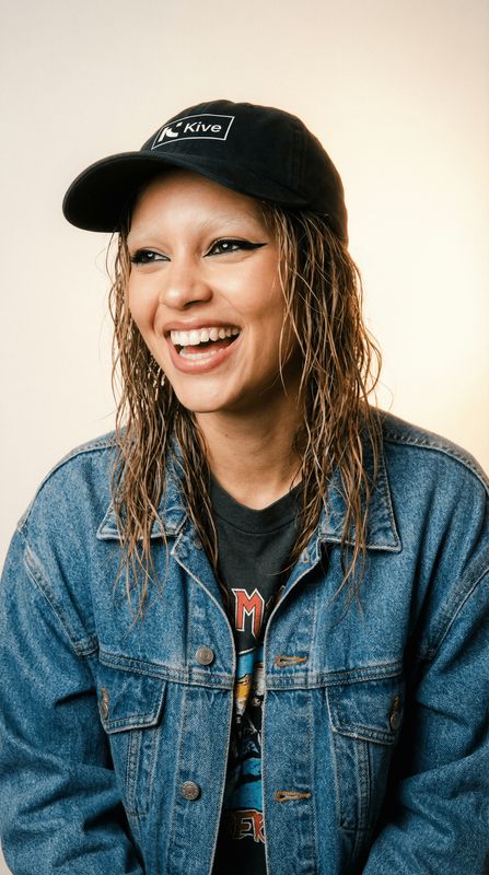 a woman with long hair wearing a denim jacket and a hat