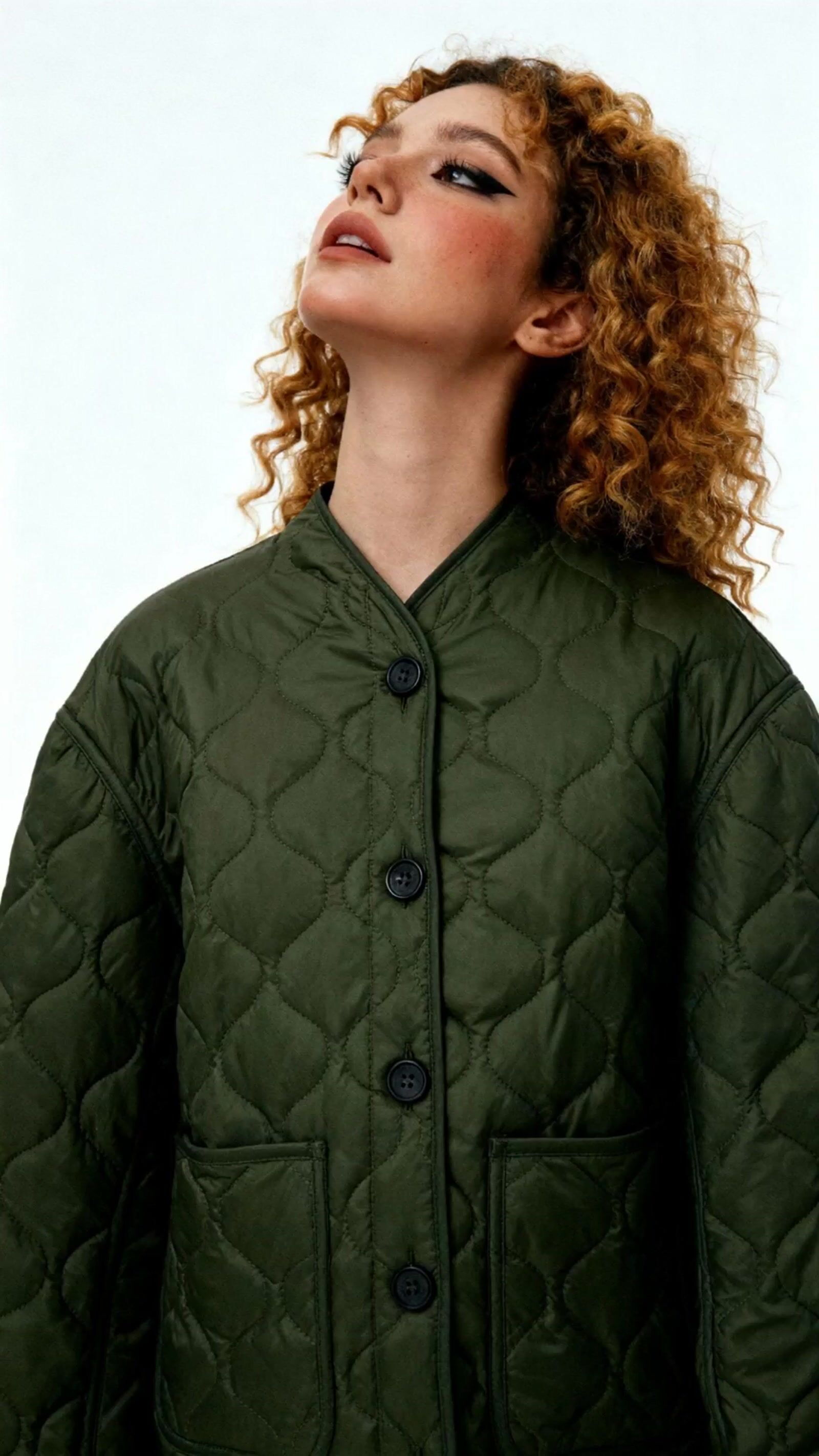 a woman with curly hair wearing a green jacket