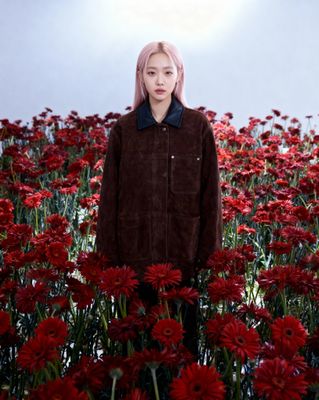 a woman standing in a field of red flowers