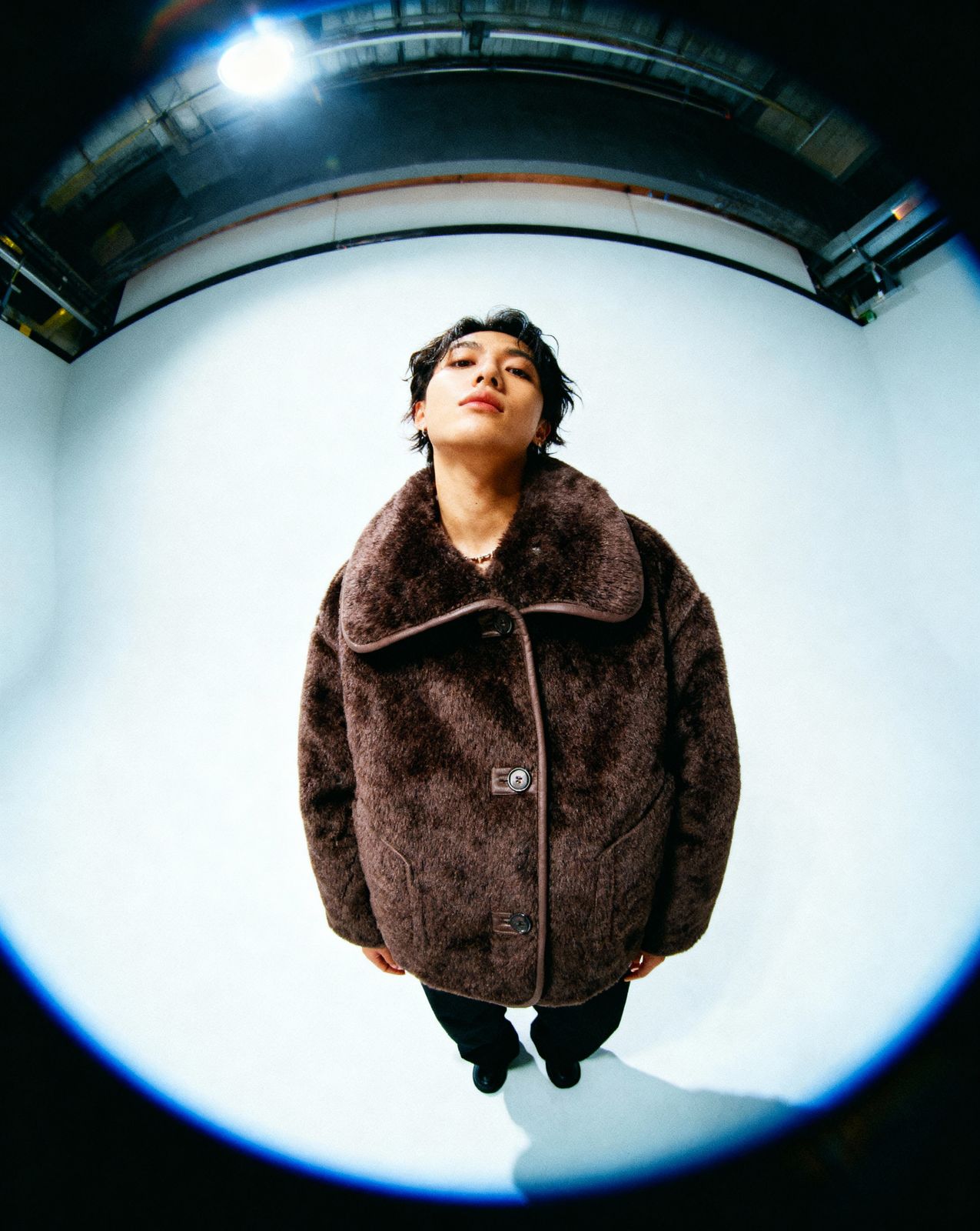 a man in a brown coat standing in front of a camera