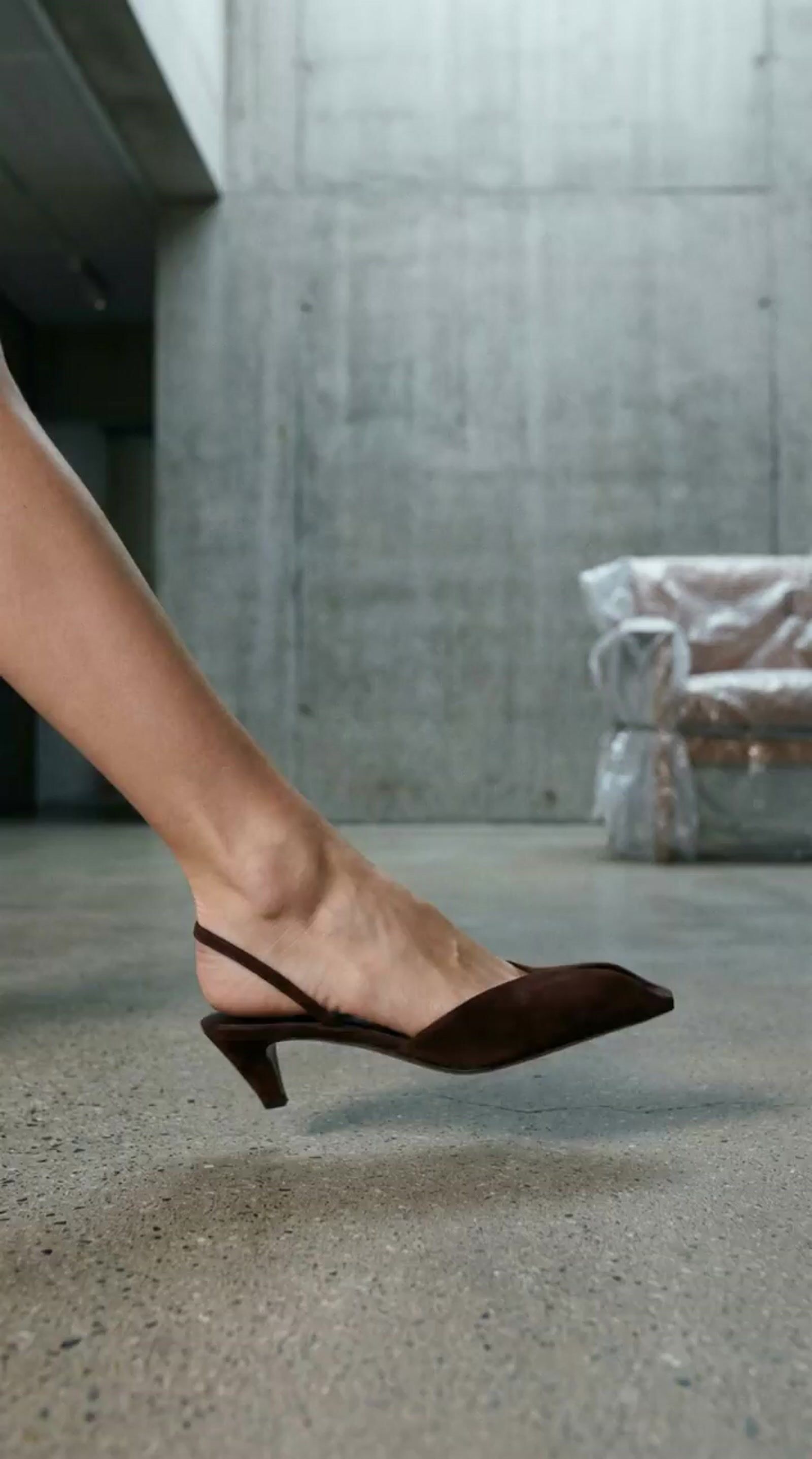 a woman's legs in high heels standing in front of a bench