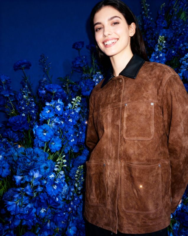a woman standing in front of blue flowers