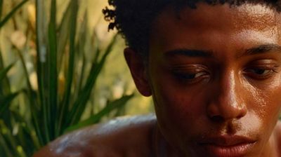 a close up of a person with a plant in the background