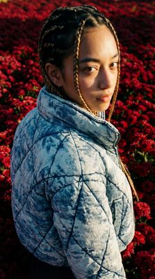 a woman with braids standing in a field of flowers
