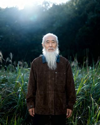 a man with a long white beard standing in a field