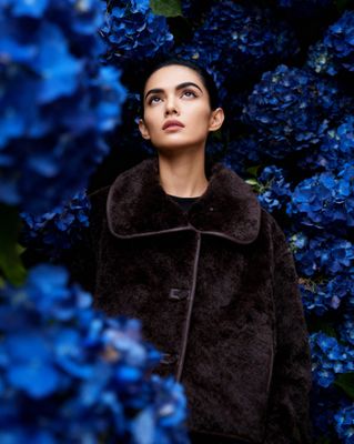 a woman standing in front of blue flowers