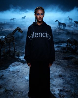 a woman standing in front of a herd of zebras