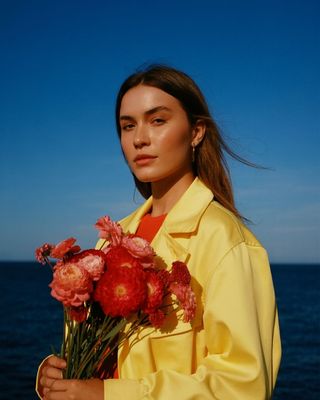 a woman in a yellow shirt holding a bouquet of flowers