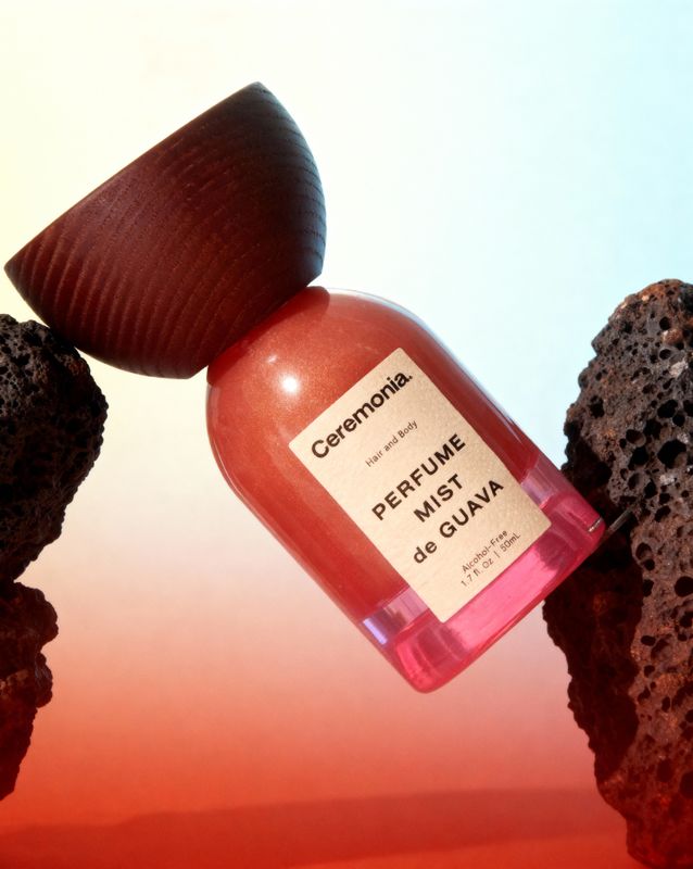 a bottle of perfume sitting on top of a pile of rocks