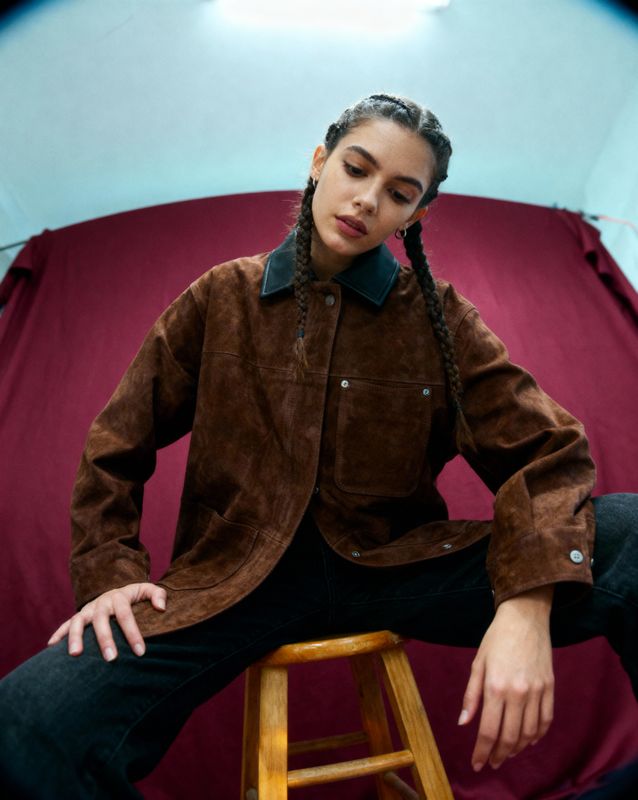 a woman sitting on a stool in front of a tent