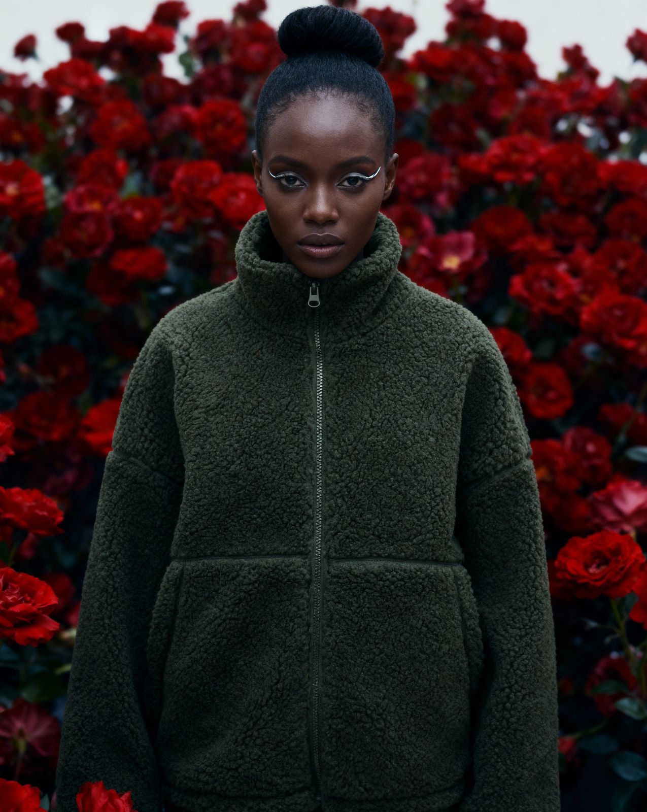 a woman standing in front of red flowers
