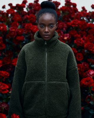 a woman standing in front of red flowers