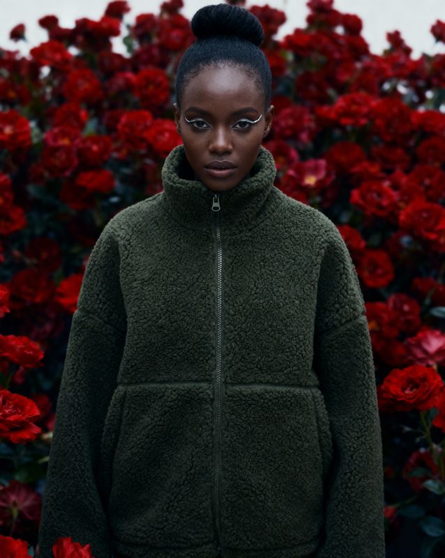 a woman standing in front of red flowers
