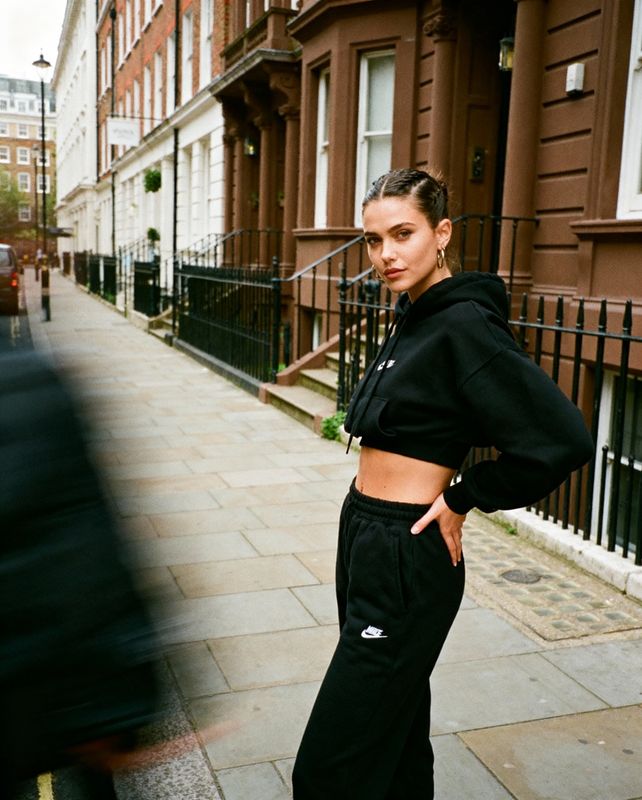 a woman standing on a sidewalk in front of a building