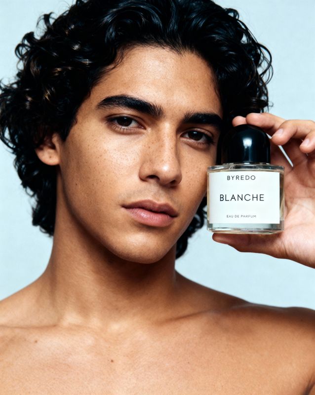 a shirtless man holding a bottle of blanche