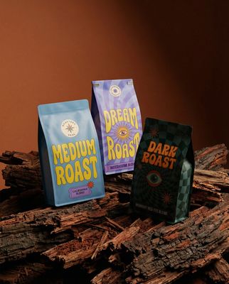 three bags of coffee sitting on top of a pile of wood