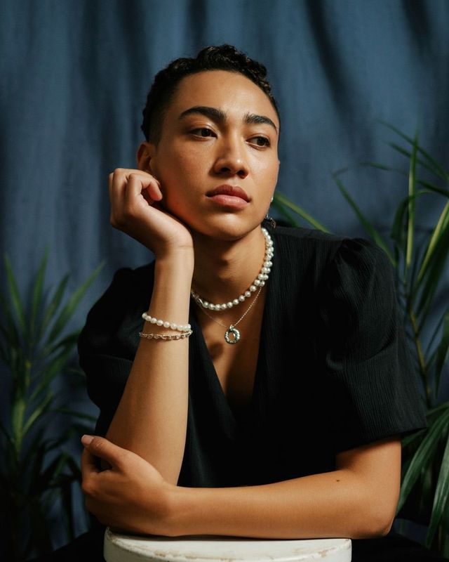 a woman wearing a pearl necklace and a black top